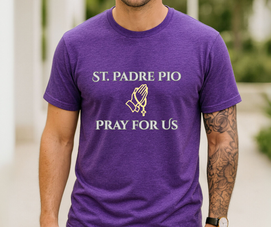 A man wearing a heather purple t-shirt with white text reading 'ST. PADRE PIO PRAY FOR US' and a gold praying hands graphic on the chest.