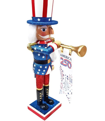 A patriotic Uncle Sam nutcracker figurine holding a gold trumpet and a banner that reads 'AMERICA 250' with fireworks graphics. The figurine features a red, white, and blue glittery design with white hair and a red, white, and blue striped hat, set against a plain white background.