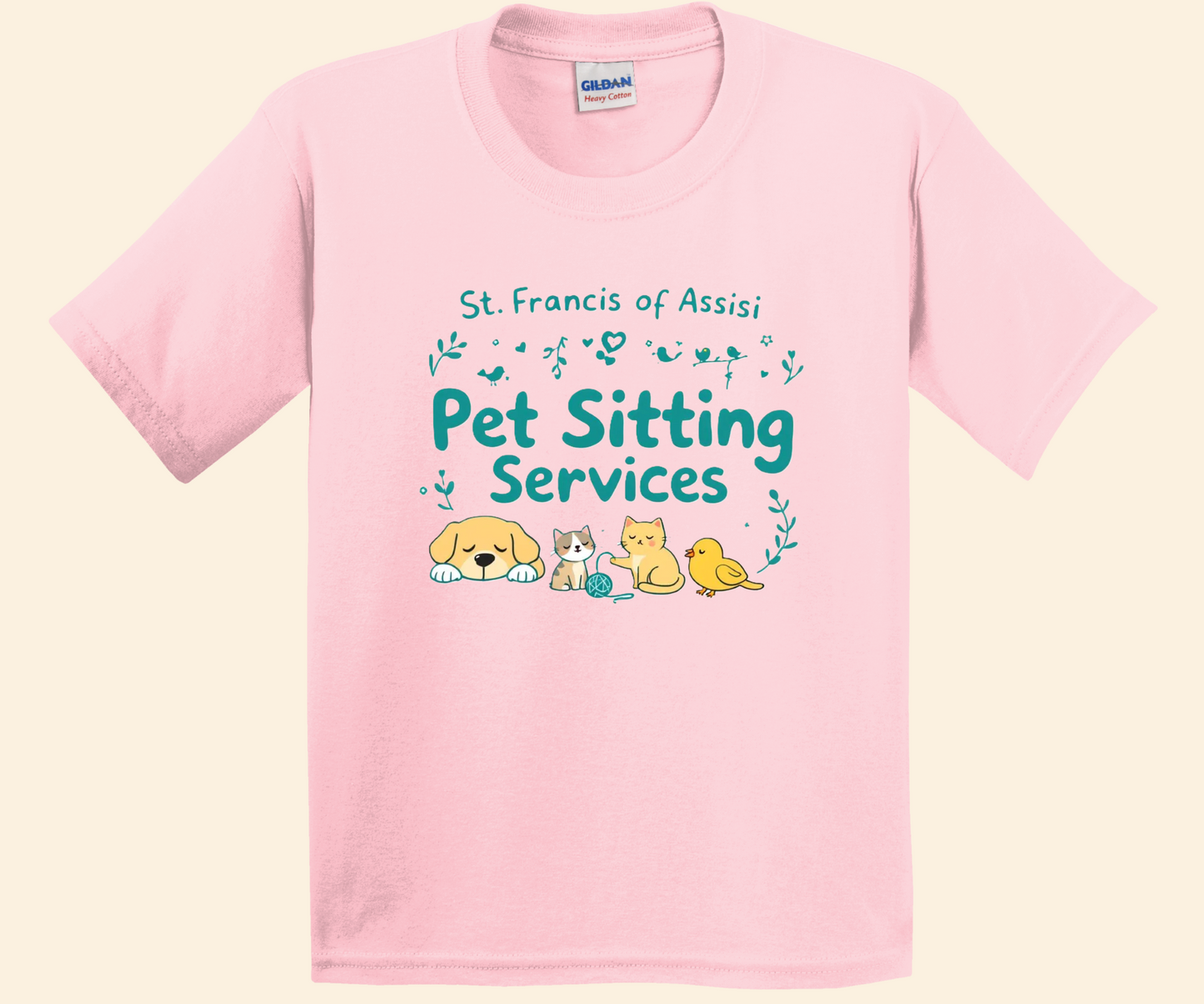 A light pink short-sleeve crewneck t-shirt featuring a 'St. Francis of Assisi Pet Sitting Services' graphic on the chest with cute illustrations of a dog, cat, and bird, displayed on a light cream background.