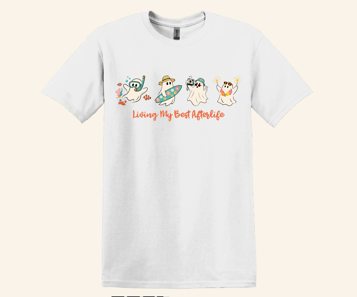 A white short-sleeve crewneck t-shirt featuring a graphic of four cartoon ghosts in different summer poses with the text 'Living My Best Afterlife' in orange script, displayed against a light beige background.