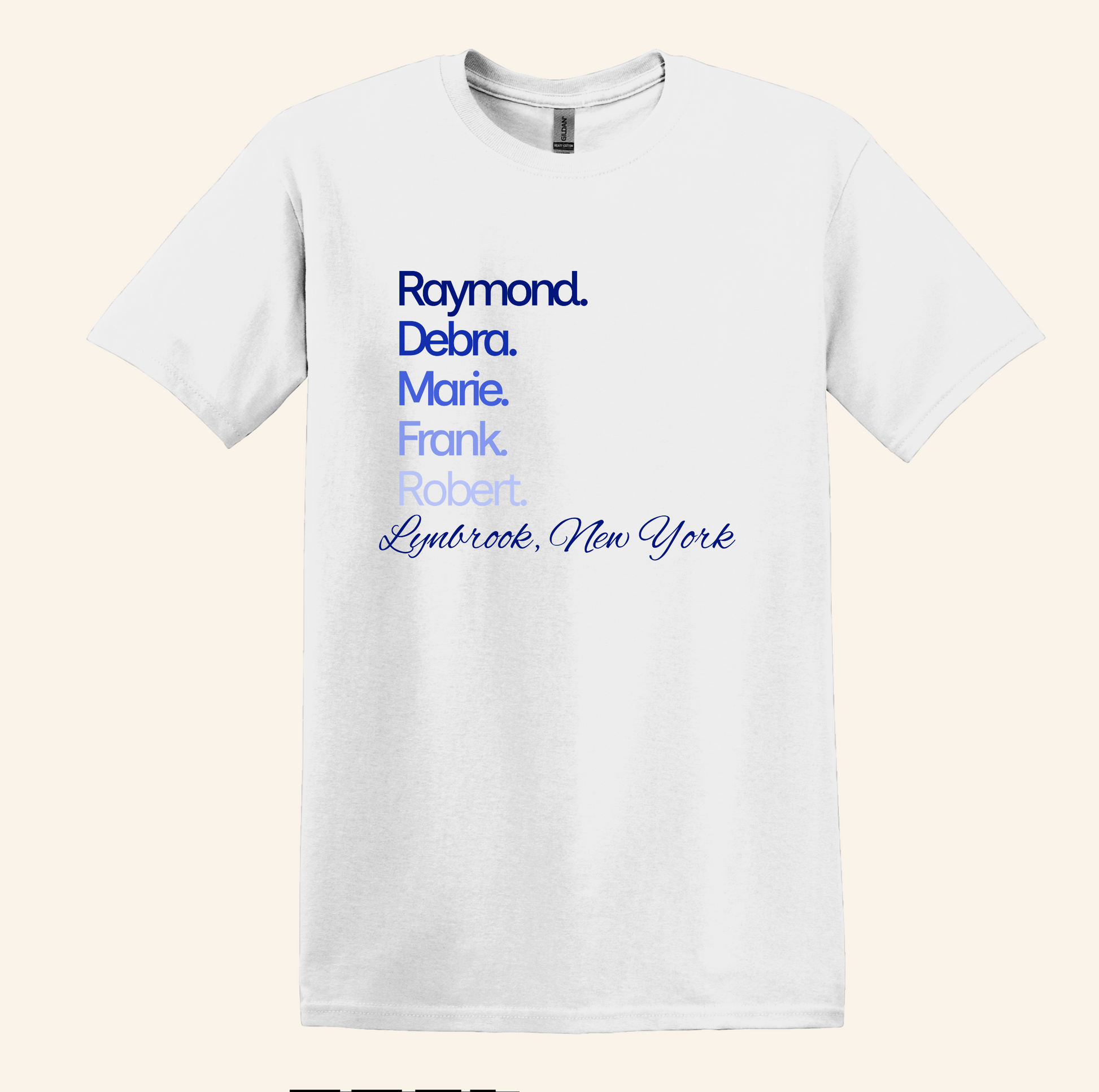 A white short-sleeve crewneck t-shirt with a blue printed text design on the chest listing names and 'Lymbrook, New York' in varying blue font weights, shown against a light beige background.