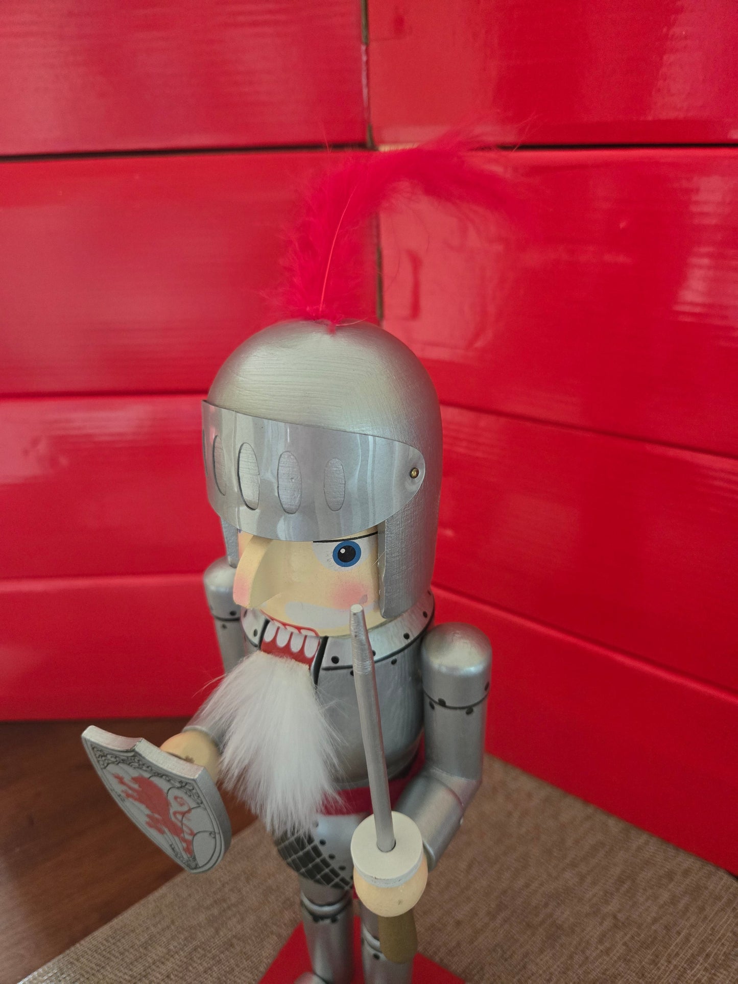 All I Need Designs 14" wooden knight nutcracker with silver armor, shield, sword, and red plume detail.