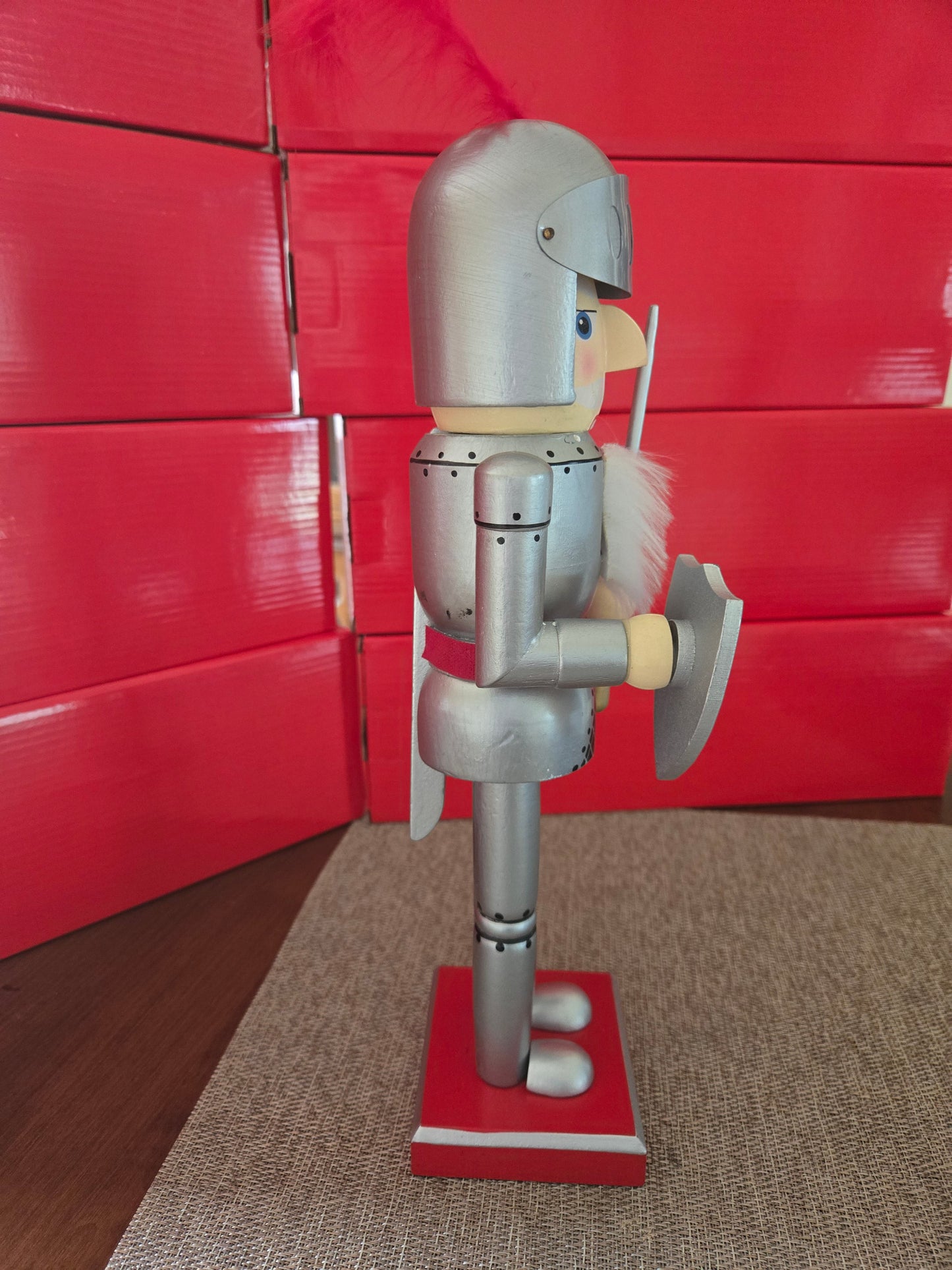 All I Need Designs 14" wooden knight nutcracker in silver armor with red plume, shield, and sword.
